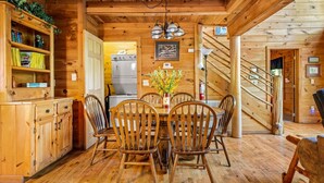 Un intérieur en bois comprenant une table à manger, des chaises, un coin cuisine et un escalier.