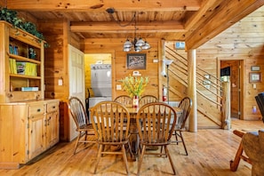 Un intérieur en bois comprenant une table à manger, des chaises, un coin cuisine et un escalier.