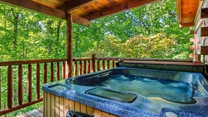 Un jacuzzi en una terraza de madera con vistas a un bosque.