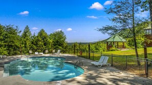 Une piscine avec des chaises longues, un belvédère et un jardin clos.