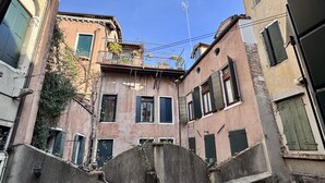 A narrow alleyway between buildings with closed shutters and a small fountain in the center. - Mozart Bis (5 min to Rialto's Bridge) (Venecia)