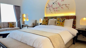 A hotel room with a large bed, a sofa, a desk, and a wall-mounted lamp.