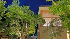 A nighttime pathway leading to a building with a traditional facade, surrounded by trees and a well-maintained garden. - Sost Serena Hotel  (Sost)