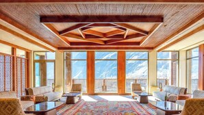 A spacious room with a large window offering a mountain view, a patterned carpet, and wooden furniture. - Sost Serena Hotel  (Sost)