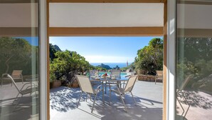 A patio with a table and chairs, a view of the ocean, and a mountain in the background. - Villa Smeralda New: Sea View, Private Pool and Air Conditioning (Costa Paradiso)