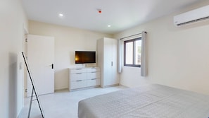 Ein Schlafzimmer mit Bett, Fernseher, Kleiderschrank und Fenster.