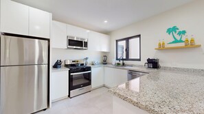 Una cocina moderna con electrodomésticos de acero inoxidable, encimera de granito y ventana con vistas.