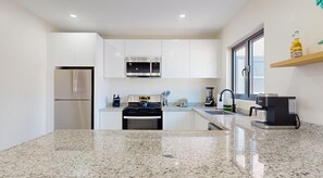 A modern kitchen with white cabinets, a stainless steel refrigerator, a microwave, a stove, and a coffee maker. - Palm Beach Hideaway #8 - New Construction 2Bedrooms 2bathrooms Pool/Rooftop (Noord)