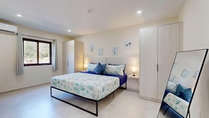 A bedroom with a bed, bedside tables, a wardrobe, and a window. - Palm Beach Hideaway #8: Poolfront Corner 2BR with Wraparound Patio (Noord)