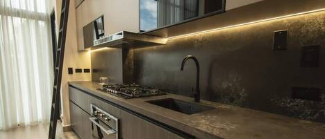 Une cuisine moderne équipée d’une cuisinière à gaz, d’un évier et d’appareils électroménagers en acier inoxydable.