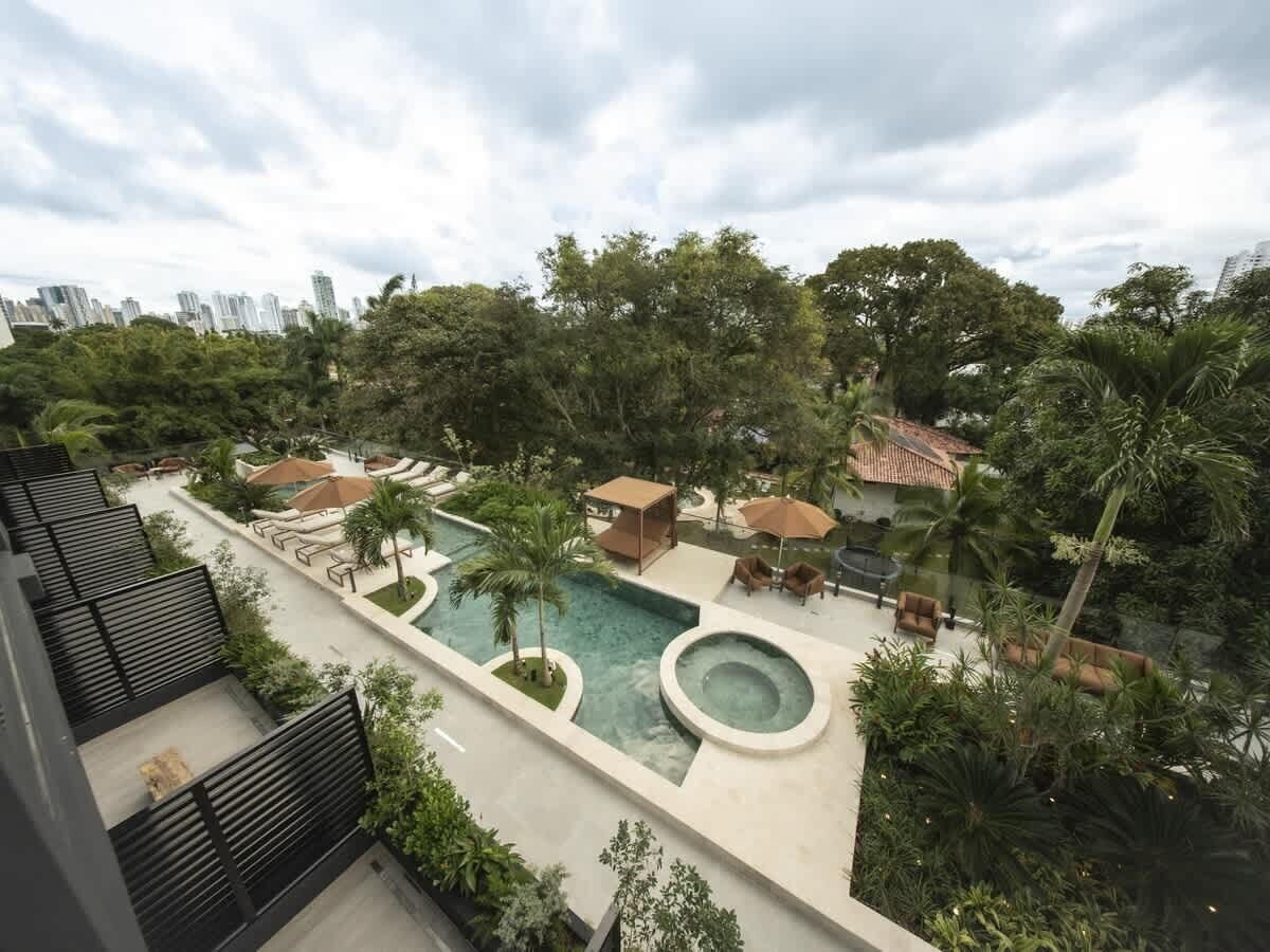 A rooftop pool area with a hot tub, lounge chairs, and palm trees.