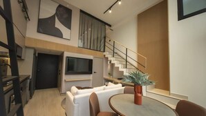 A modern living room with a sofa, a dining table, and a staircase leading to an upper level. - Smart Loft-Style 1br Apt near to shops (Ciudad de Panamá)