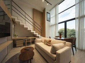 A modern living room with a sofa, coffee table, and a staircase.
