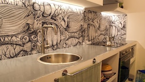 A kitchen with a stainless steel sink, a faucet, and a backsplash with a fish and plant pattern. - Conti & Moroni House  (Calenzano)