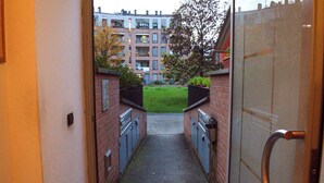 A narrow alleyway leading to a building with a brick facade and a metal gate. - Conti & Moroni House  (Calenzano)