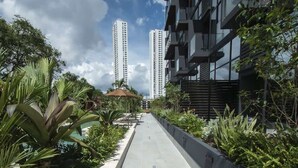 A pathway lined with tropical plants and a modern building with balconies. - Your Modern Brand-New Temporary Home in Panama (Ciudad de Panamá)