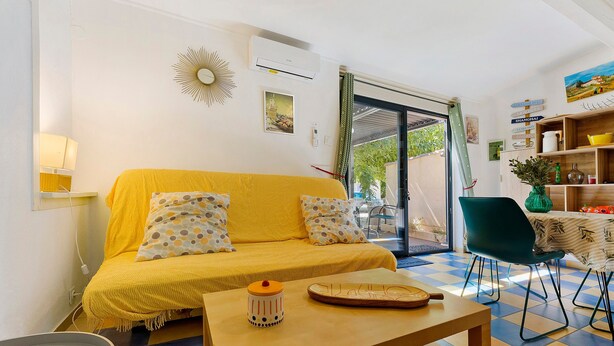 Ein Wohnzimmer mit einem gelben Sofa, einem kleinen Tisch und einem Essbereich mit einem Stuhl.