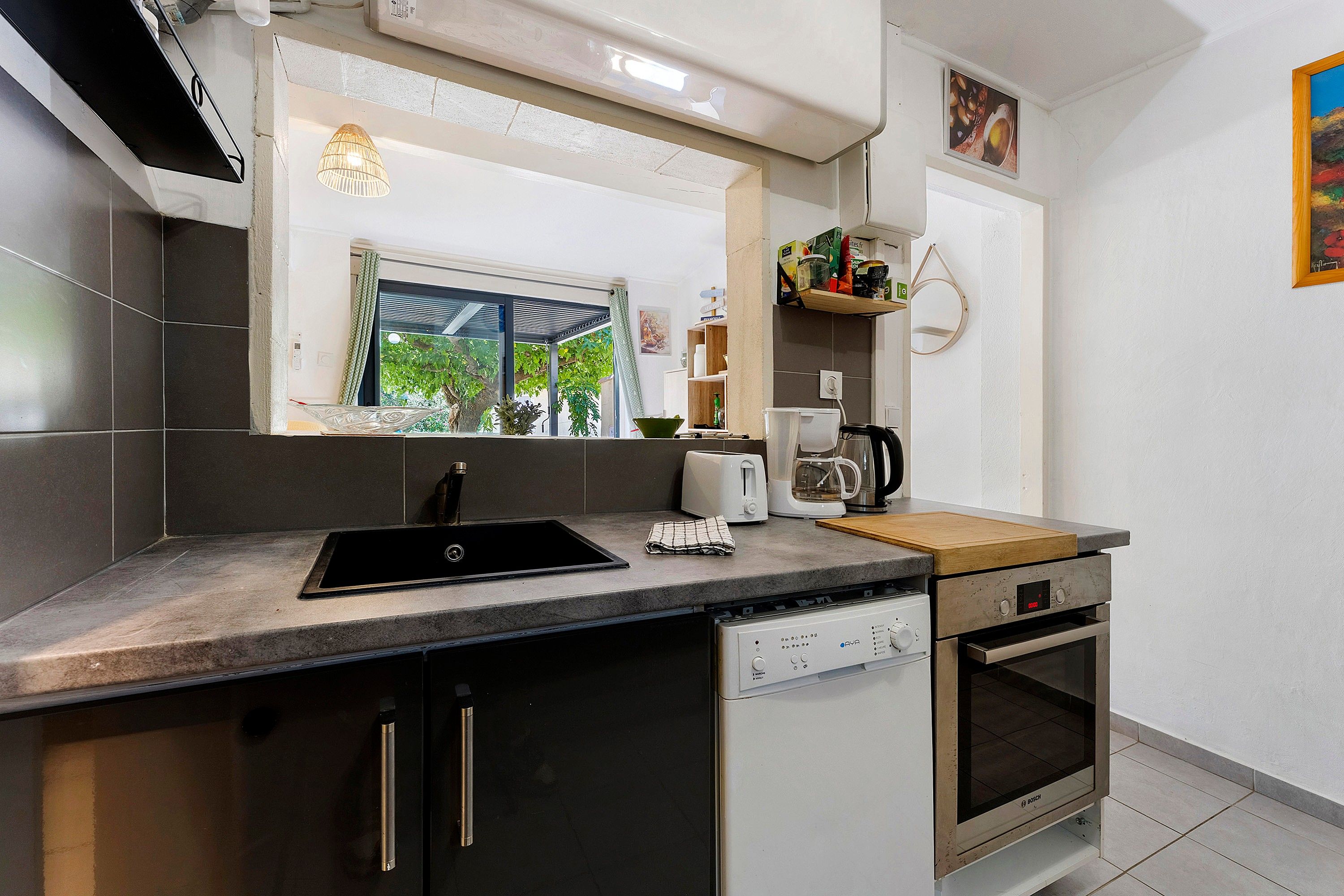 Een moderne keuken met een zwarte spoelbak, een koffiezetapparaat en een Bosch oven.