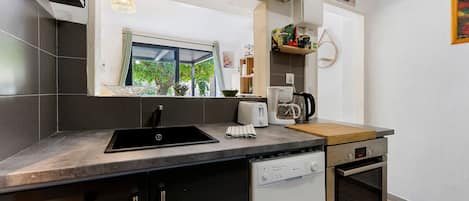 Een moderne keuken met een zwarte spoelbak, een koffiezetapparaat en een Bosch oven.