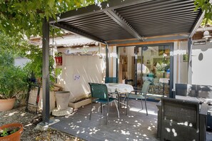 An outdoor seating area with a table and chairs, a pergola, and potted plants. - Gîte Les Garrigues – Modern Comfort Near Les Baux-de-Provence, Sleeps 3 (Mouriès)