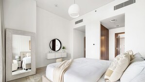 A modern bedroom with a large bed, a round mirror, a white console table, and a large window. - 2BR M Huge Terrace Direct Canal Access (Dubai)