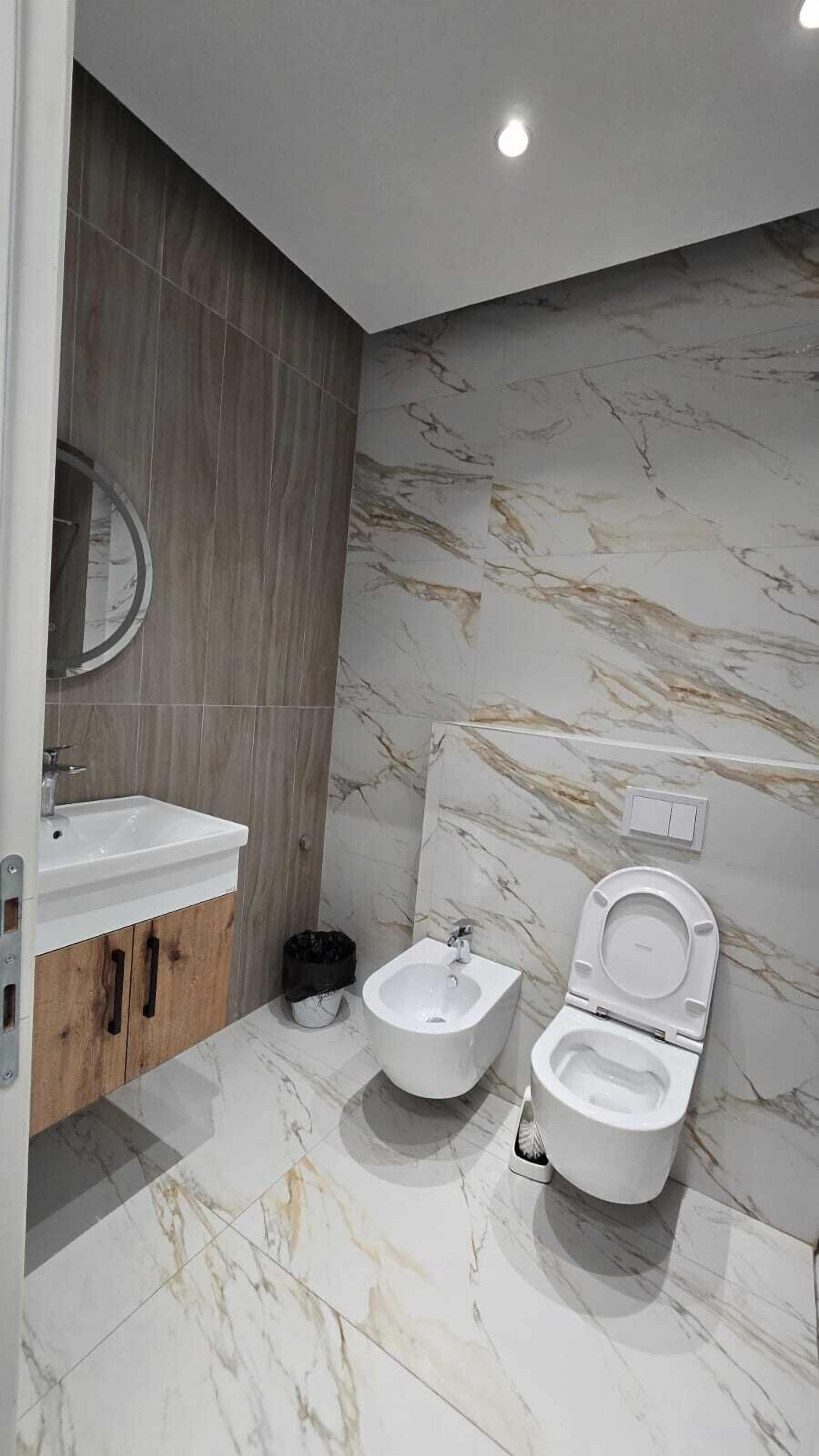 Une salle de bain moderne équipée d’un bidet, d’un lavabo et d’un miroir.