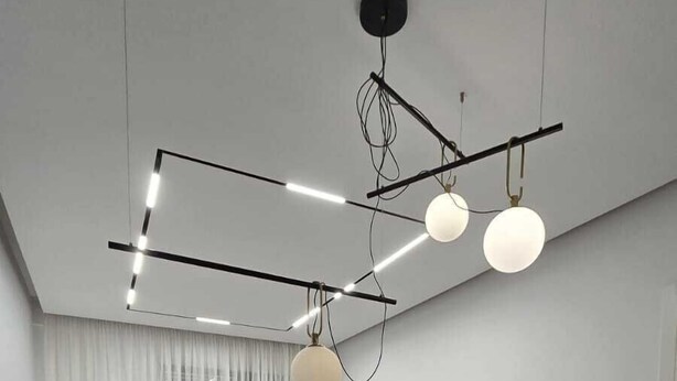 Un salon moderne comprenant un coin repas, un ensemble de canapés, un téléviseur à écran plat et un luminaire suspendu au plafond.