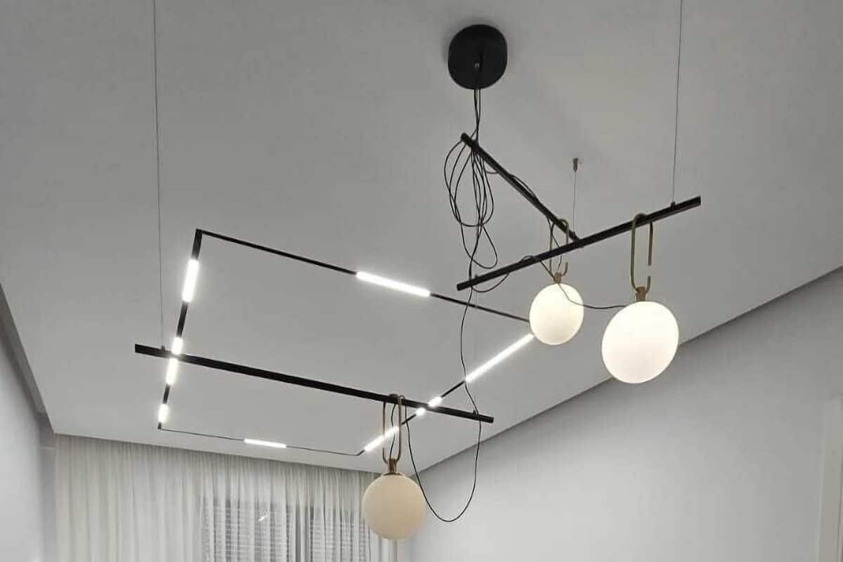 Un salon moderne comprenant un coin repas, un ensemble de canapés, un téléviseur à écran plat et un luminaire suspendu au plafond.