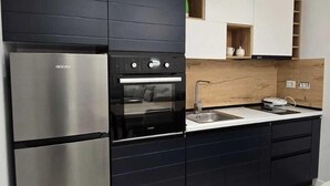 Une cuisine moderne avec des meubles noirs, des appareils en acier inoxydable et un plan de travail en bois.