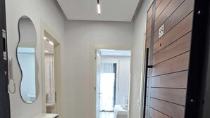 Un couloir avec une armoire blanche, un miroir et une porte en bois.