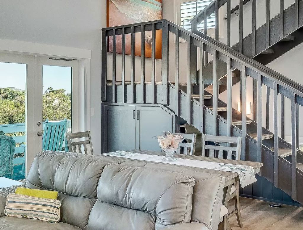 A modern interior with a staircase, a dining area with a table and chairs, and a leather sofa.
