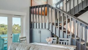 Um interior moderno com uma escada, uma área de jantar com mesa e cadeiras, e um sofá de couro.
