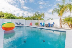 A swimming pool with clear blue water, surrounded by a white fence, and several colorful chairs. - Barefoot Bliss - Heated Pool, Walk to the Beach, Ping Pong (St. Augustine)