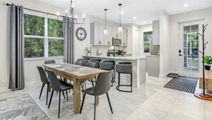 A modern kitchen with white cabinets, a central island, and pendant lighting. - Peaceful Naples Gateway (Naples)