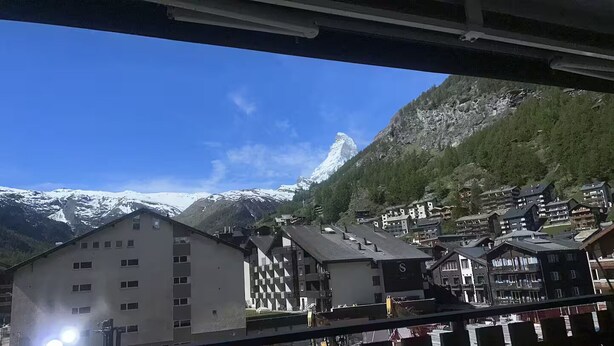 En bergsstad med byggnader och ett snötäckt bergstopp i bakgrunden.