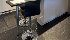 Ett modernt kök med en central köksö, barstolar och en inbyggd ugn.