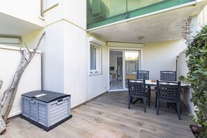 A patio with a table and chairs, a storage unit, and a door leading to an interior space. - Seaside Apartment in Saint-Cyprien-Plage (66750), Lagune Area (Saint-Cyprien Plage)