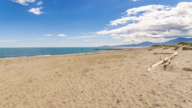 A beach with a clear sky, sandy shore, and distant mountains. - Seaside Apartment in Saint-Cyprien-Plage (66750), Lagune Area (Saint-Cyprien Plage)