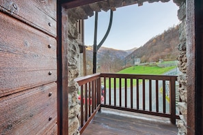 Un balcon en bois offrant une vue sur un paysage verdoyant et des montagnes.