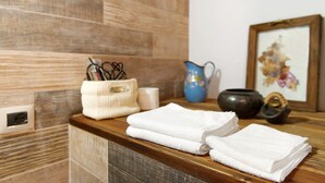 A bathroom with a wooden vanity, a towel holder, a blue pitcher, and a framed picture. - Holiday Home 'Maison Core' with Mountain View and Wi-Fi (Fontainemore)