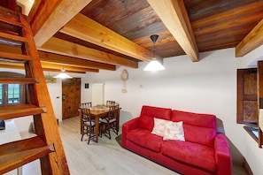 Un intérieur en bois avec un canapé rouge, une table à manger et des chaises.