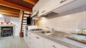 A kitchen with a stone fireplace, wooden ceiling beams, a stainless steel sink, and a tiled backsplash. - Holiday Home 'Maison Core' with Mountain View and Wi-Fi (Fontainemore)