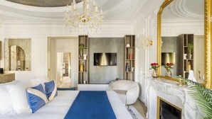 Een luxueuze slaapkamer met een groot bed, een open haard, een televisie en een boekenkast.