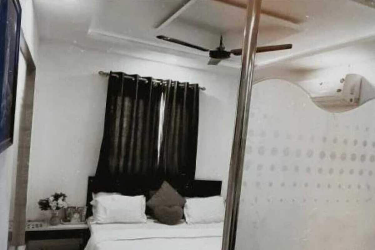 A bedroom with a bed, a nightstand, a ceiling fan, and a window with curtains.