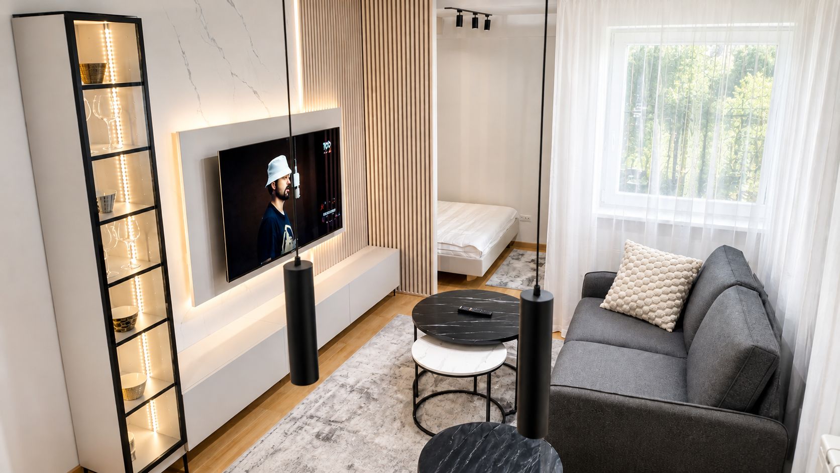 A modern living room with a flat-screen TV, a sofa, a coffee table, and a side table.