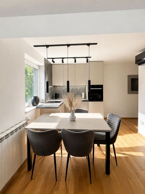 A modern kitchen with a central island, pendant lighting, and a view of the outdoors. - Luxury Prime Apartments with Parking (Sarajevo)