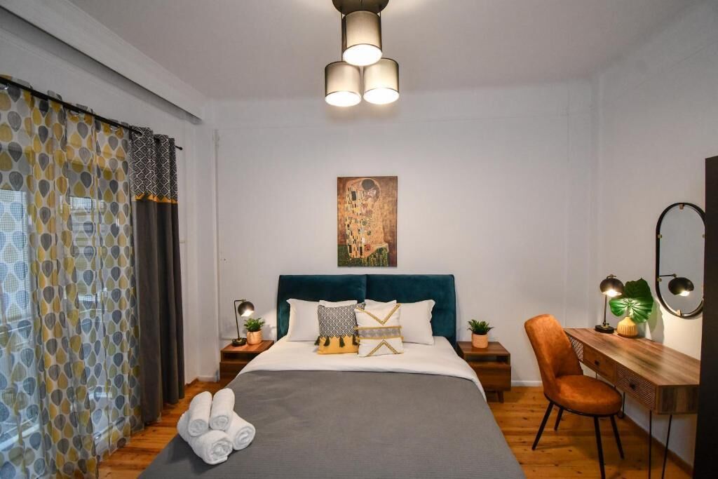 Een keurig opgemaakt slaapkamer met een bed, nachtkastjes, een bureau en een stoel.