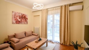 A living room with a sofa, a wooden coffee table, and a painting on the wall. - Porto Sea View Apartments - D. Gounari 5 (Thessaloniki)