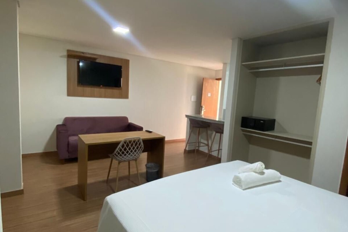 Une chambre d’hôtel équipée d’un lit, d’un bureau, d’une chaise, d’un canapé et d’un téléviseur fixé au mur.