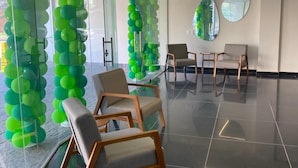 A modern waiting area with green balloon columns, comfortable seating, and a clean, reflective floor. - San Diego Suites Manhuaçu (Manhuaçu)
